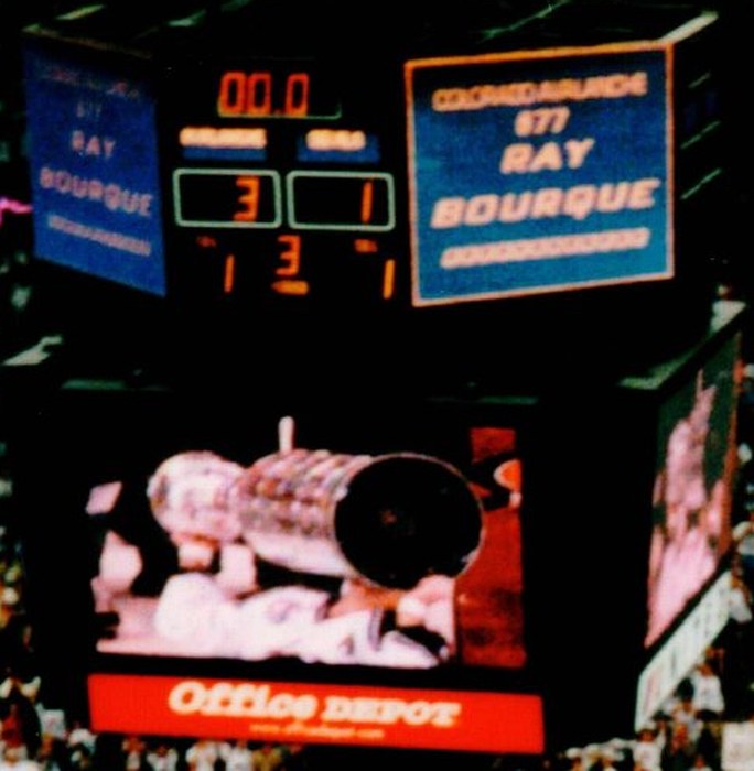 Scoreboard reading Colorado Avalanche number 77 Ray Bourque, with the Stanley Cup raised on the video screen